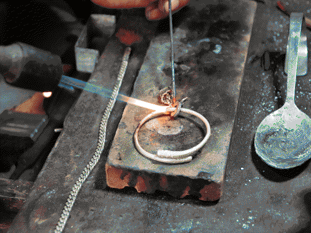Papi en train de travailler sur un bracelet en argent avec le chalumeau.