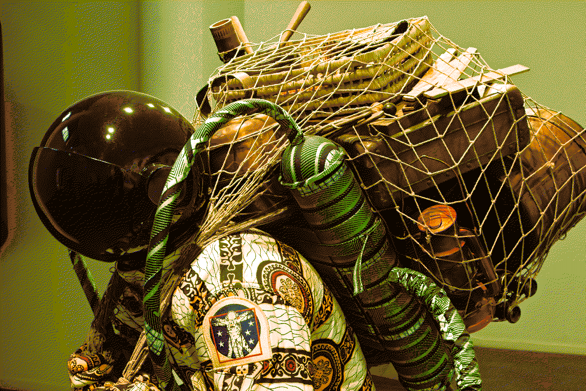 Photo de la statue d'un astronaute ou un scaphandrier habillé d'une combinaison en wax portant sur son dos un filet contenant divers objets et documents