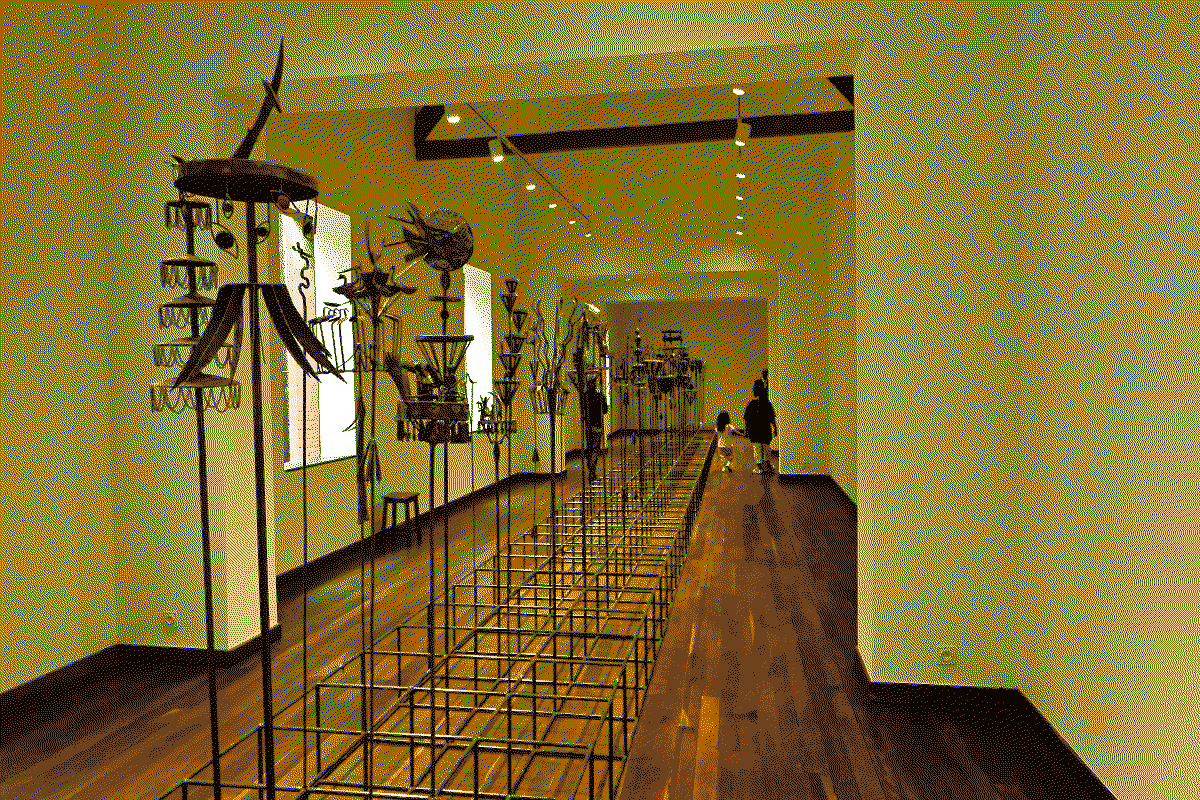 Photo d'une installation composée de 67 sculptures verticales en métal alignées en deux rangées dans un couloir de 20 mètres de long