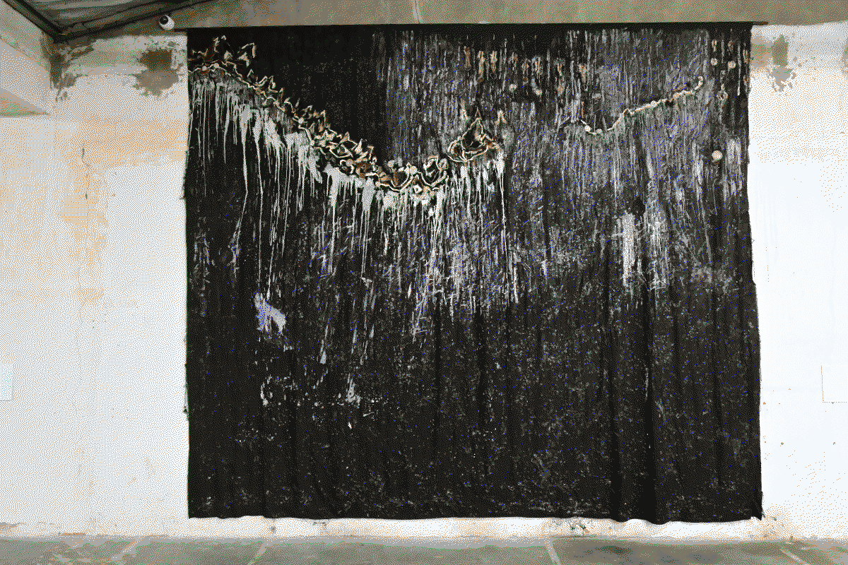 Photo de l'oeuvre Lamban'Akoho composée d'un grand tissu noir sur lequel sont peint des motifs évoquant les os de poulet et tacheté de blanc