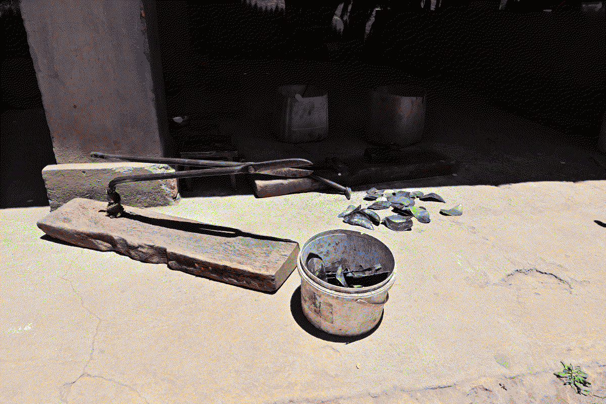 Photo de cisailles de découpe des feuilles de métal, on peut voir les écailles obtenues dans un seau à proximité